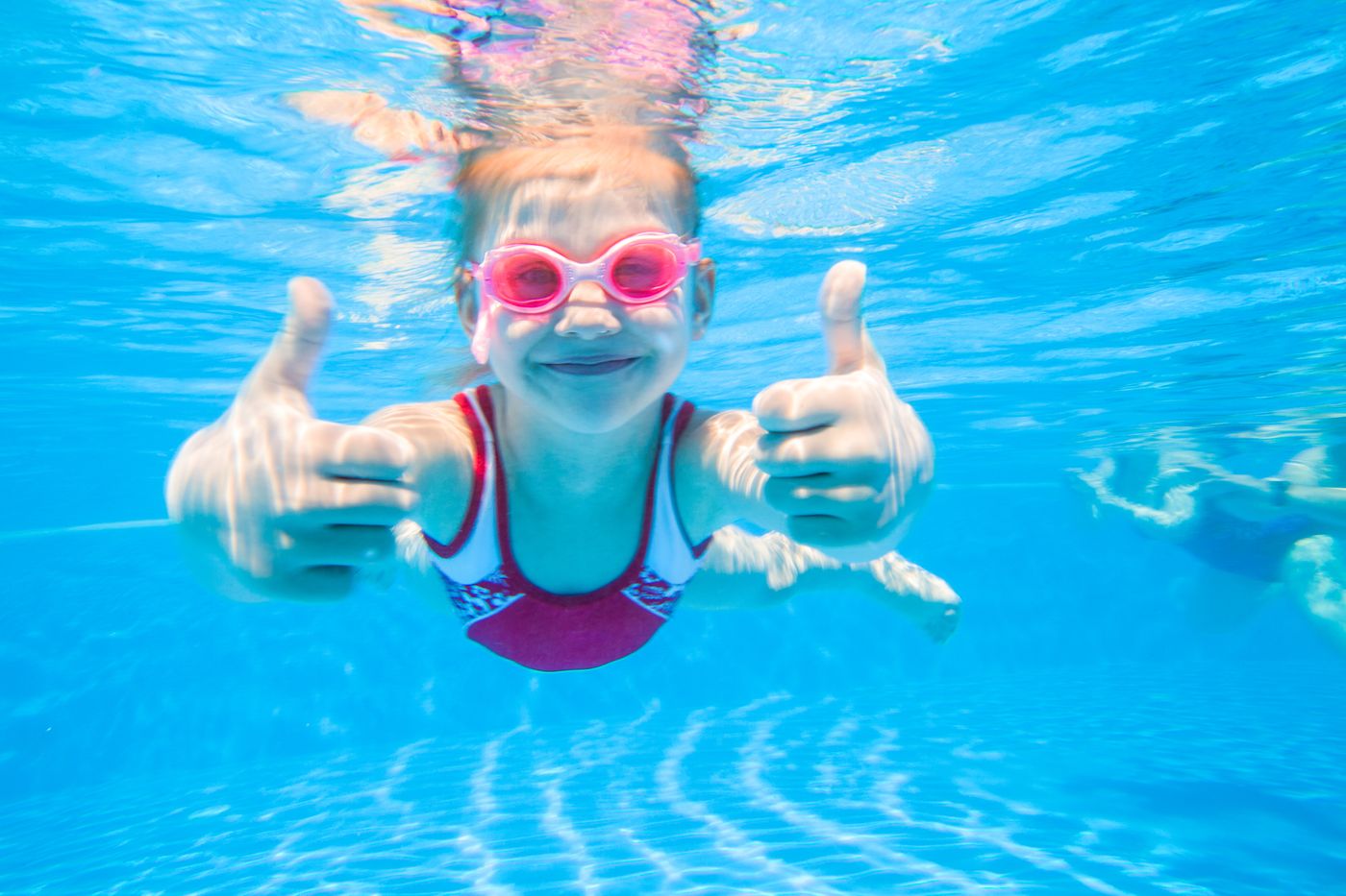 Girl swimming and giving a thumbs up underwater