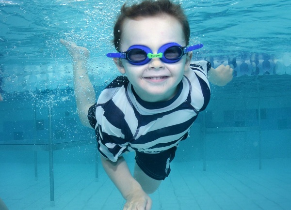 young kid swimming underwater with goggles on