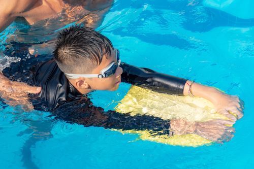 child learning how to swim with a paddle board