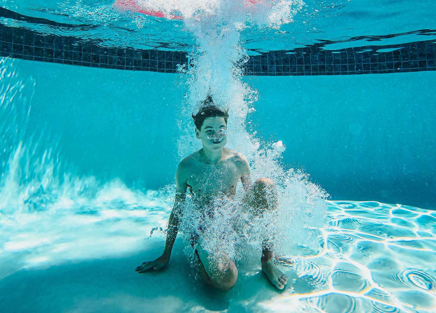 a kid jumping into a pool and holding their breath